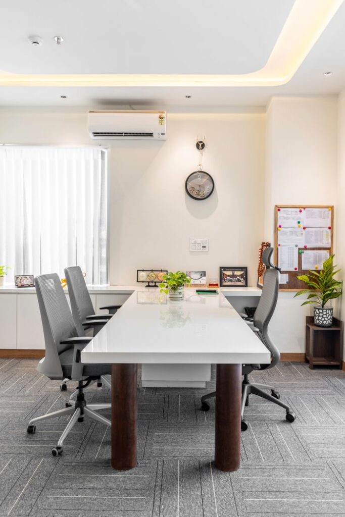 Bright and minimalist conference room with white table and grey chairs.