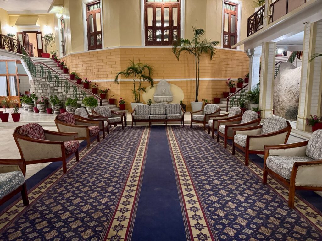 Spacious, elegantly decorated hotel lobby with classic furniture and lush plants.