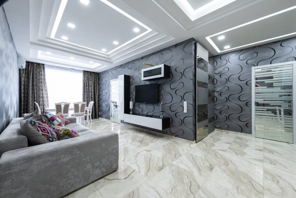 Comfortable gray sofa with pillows placed opposite TV in living room with gray walls in contemporary apartment in daylight